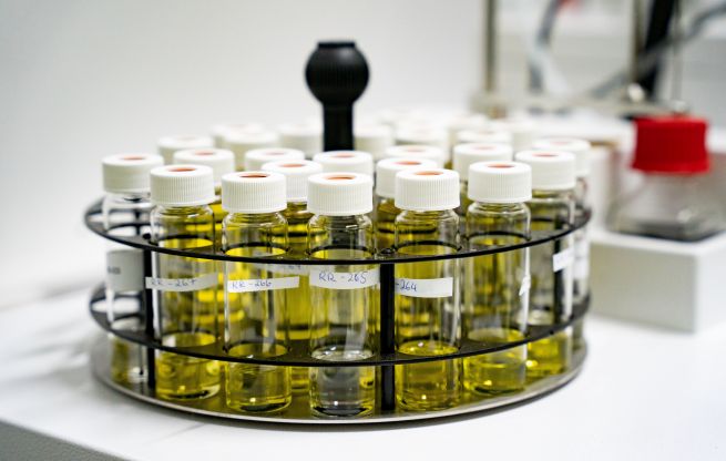 In a carousel on a laboratory apparatus are sample vials containing a yellow liquid.