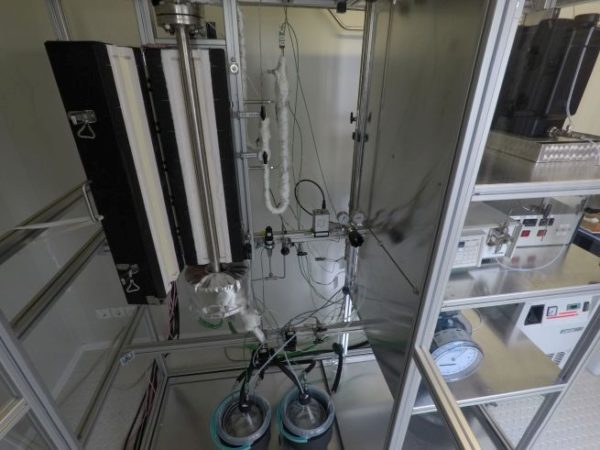 View of a test bench in the laboratory with measuring equipment, gas cylinders, pipes and cables.